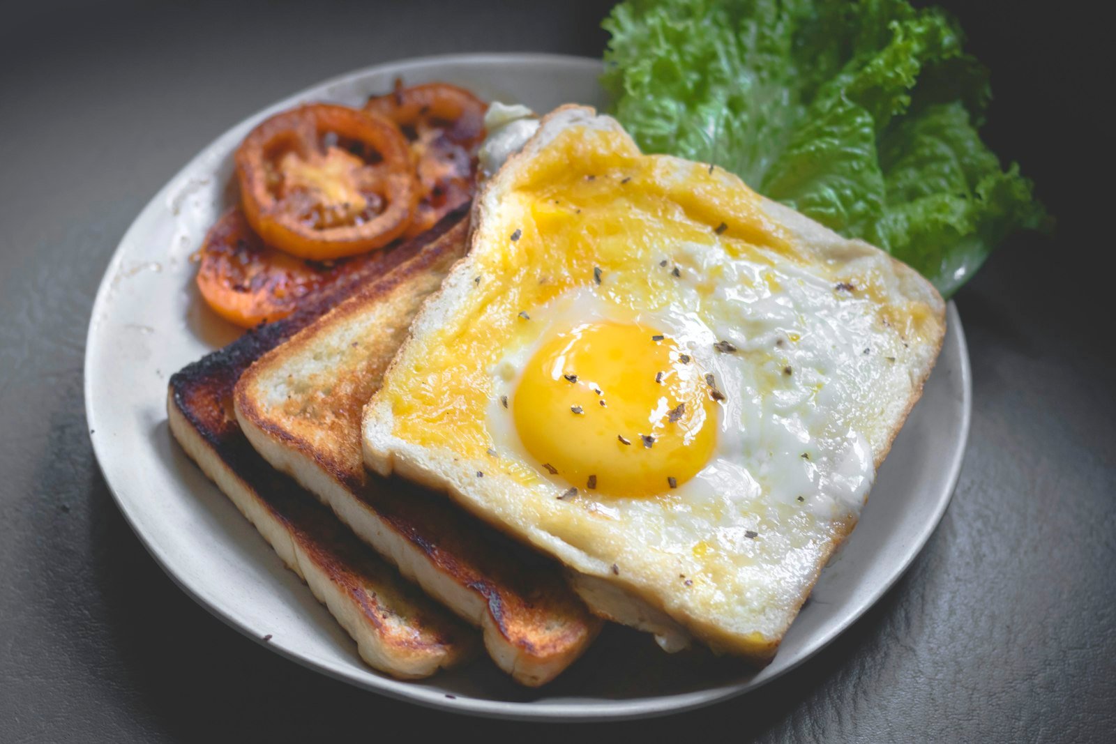 A full English breakfast plate with egg, sausage, beans and toast.